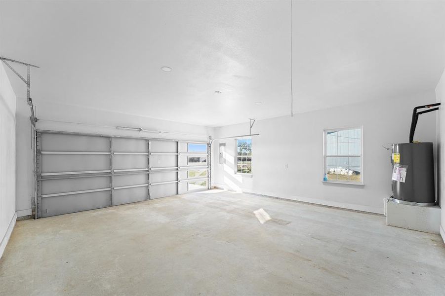 Garage featuring electric water heater and baseboards