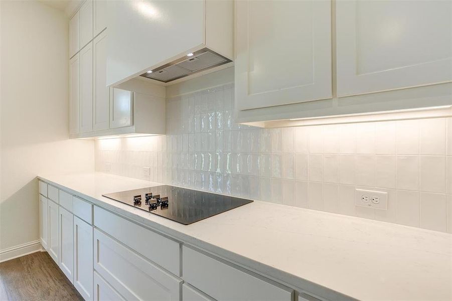 Kitchen with white cabinetry, black electric cooktop, tasteful backsplash, premium range hood, and hardwood / wood-style floors