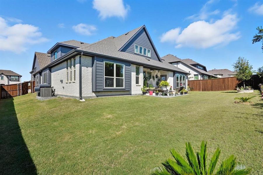 Back of house featuring a fenced backyard, brick siding, a patio, and roof with shingles