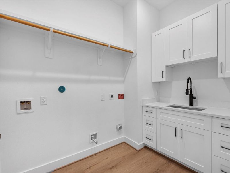Laundry room with full lower and overhead cabinetry with sink and matching counters