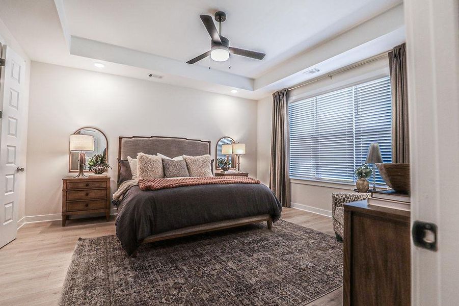 Bedroom with light wood finished floors, a tray ceiling, a ceiling fan, and recessed lighting