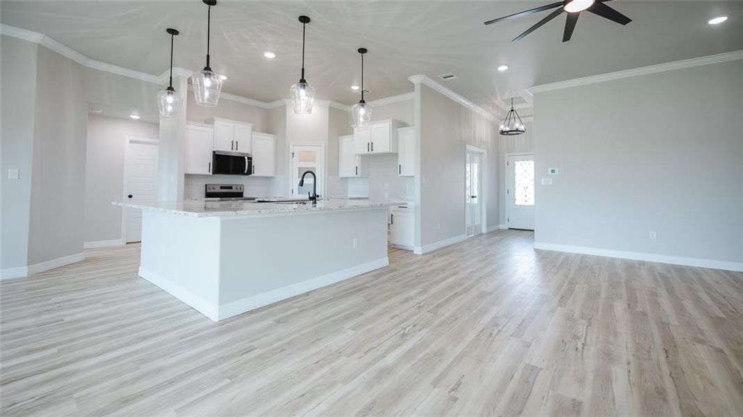 Kitchen with a ceiling fan, light wood finished floors, a large island, stainless steel appliances, and recessed lighting Kitchen with a ceiling fan, light wood finished floors, a large island, stainless steel appliances, and recessed lighting