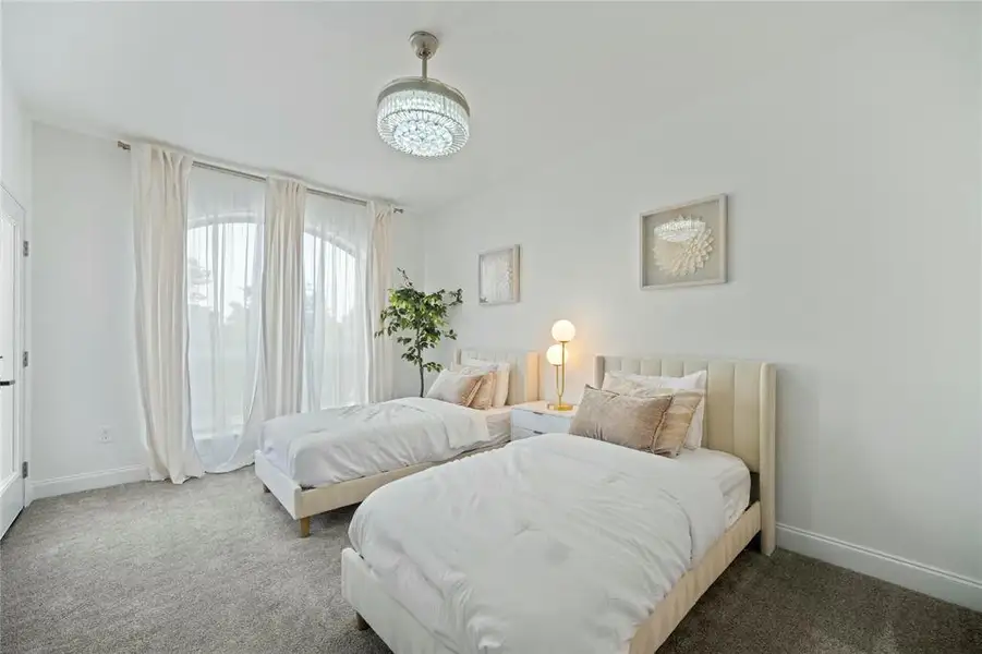 Carpeted bedroom featuring baseboards and a chandelier