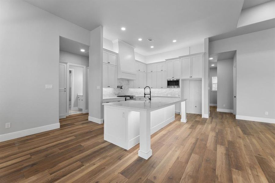 Kitchen featuring stainless steel microwave, sink, white cabinets, and a kitchen island with sink