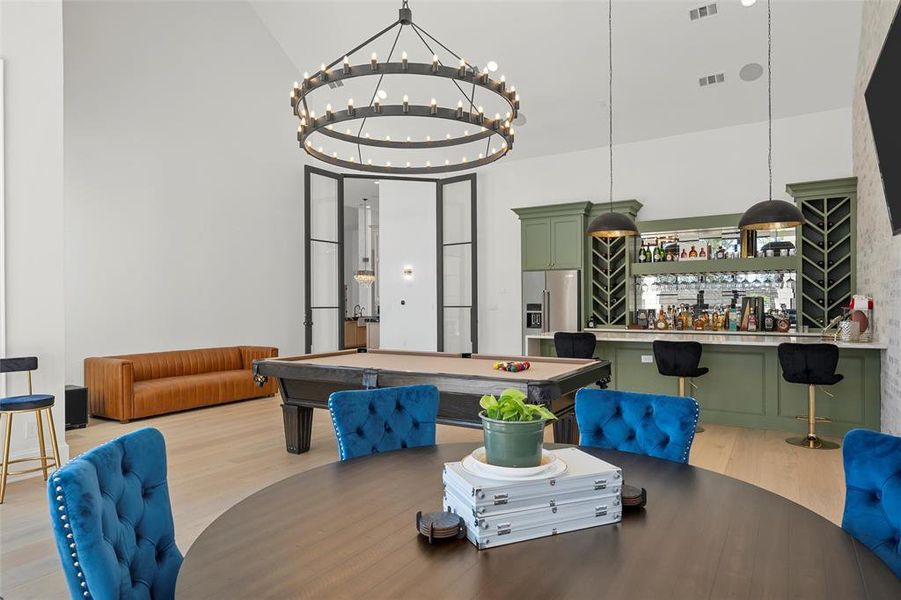 Dining room featuring billiards, light wood-style floors, high vaulted ceiling, and bar area