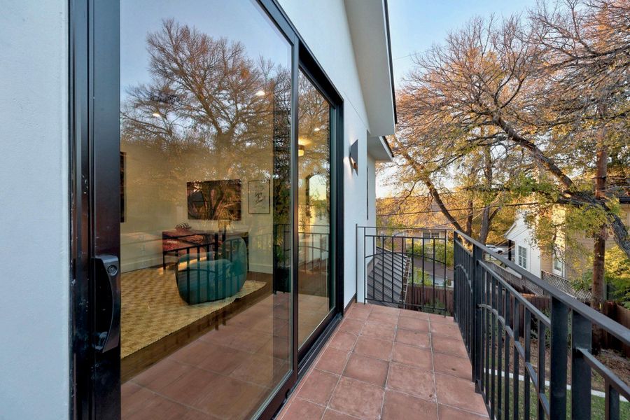 Outdoor balcony featuring terracotta tile flooring and black wrought iron railings