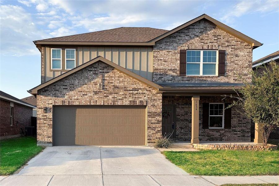 View of front of property with a porch, concrete driveway, a front lawn, brick siding, and roof with shingles View of front of property with a porch, concrete driveway, a front lawn, brick siding, and roof with shingles