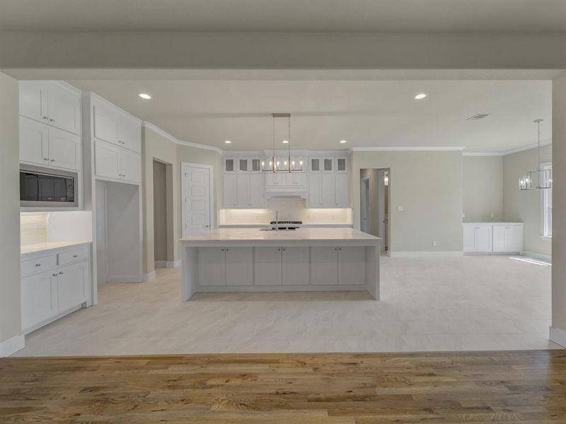 Kitchen with a chandelier, crown molding, white cabinetry, recessed lighting, and light wood-style floors Kitchen with a chandelier, crown molding, white cabinetry, recessed lighting, and light wood-style floors