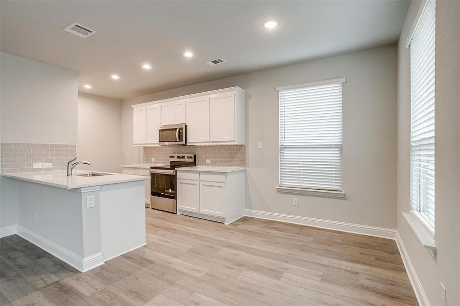 Kitchen with visible vents, stainless steel appliances, a sink, and light countertops