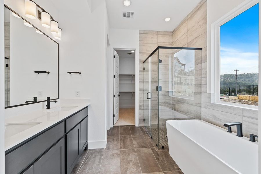 Primary bathroom with free standing tub and separate shower opens to closet