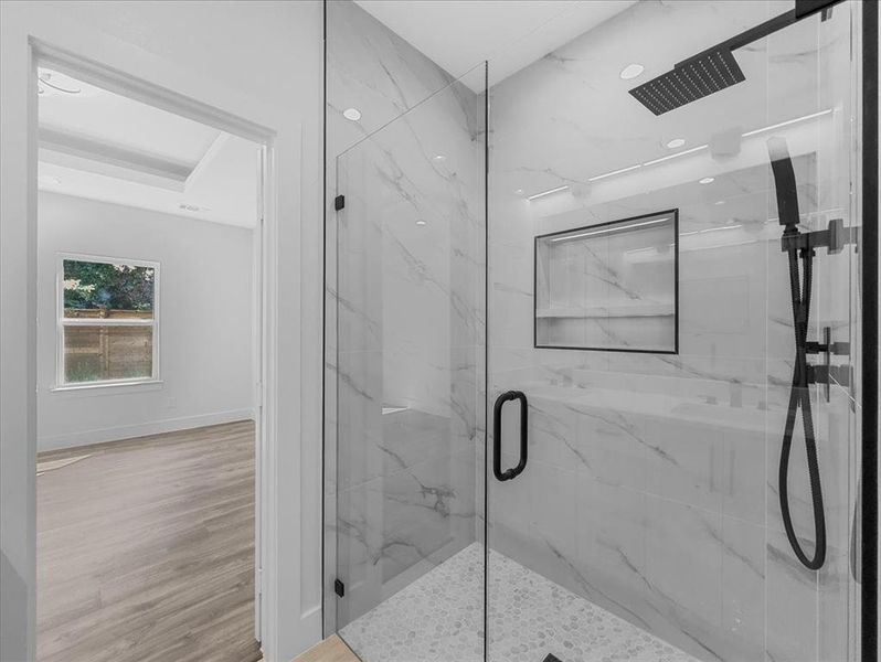 Bathroom with a marble finish shower and wood finished floors Bathroom with a marble finish shower and wood finished floors