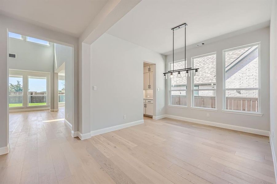 Unfurnished dining area with light hardwood / wood-style floors, an inviting chandelier, and a wealth of natural light