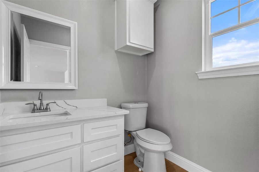 Half bath with vanity and wood finished floors located in the 5 car garage