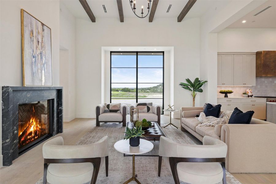 Living area with a chandelier, light wood finished floors, a fireplace, beam ceiling, and visible vents Living area with a chandelier, light wood finished floors, a fireplace, beam ceiling, and visible vents