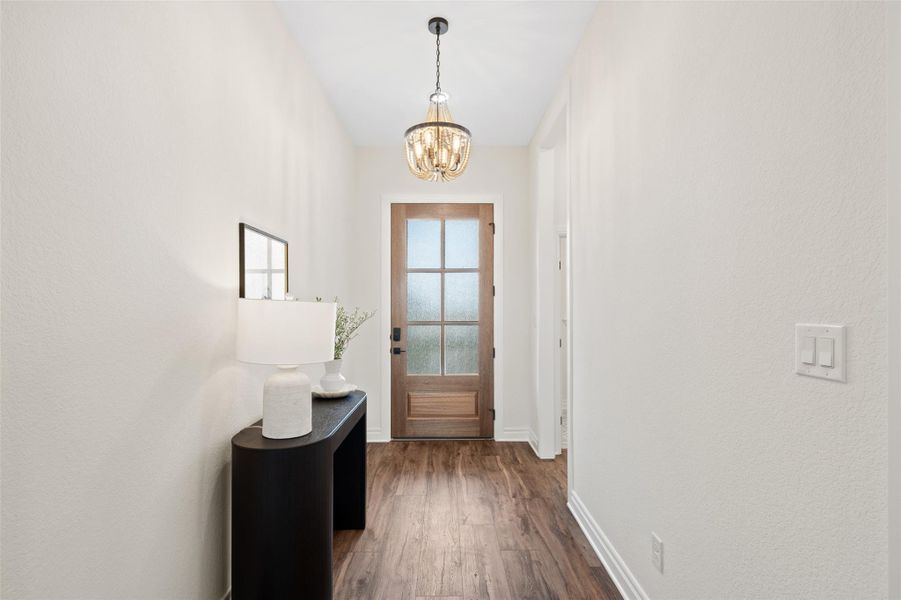 Entryway with wood finished floors, a chandelier, and a textured wall Entryway with wood finished floors, a chandelier, and a textured wall