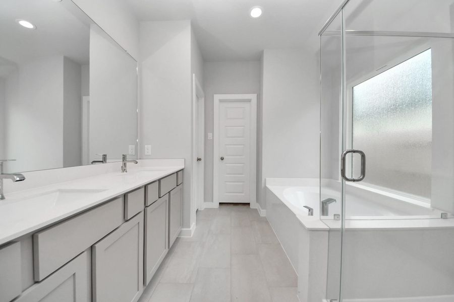 Escape to a spa-like oasis in this primary bathroom. Enjoy a walk-in shower with tile surround, a separate garden tub with custom detailing, and an elegant vanity featuring light countertops, modern hardware, and beautiful vanity lights. Experience luxury and relaxation in every detail.