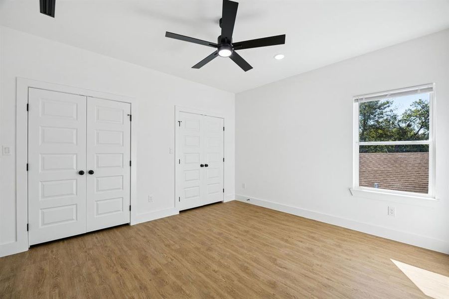 Unfurnished bedroom with two closets, light wood-type flooring, recessed lighting, and ceiling fan