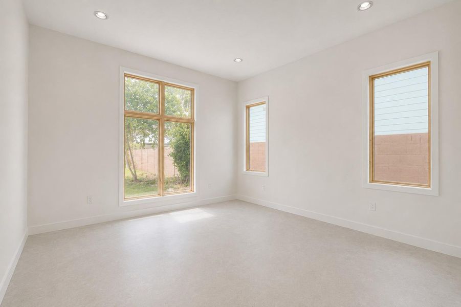 Spacious room featuring multiple windows with natural wood frames, recessed lighting, neutral wall tones, and light-colored flooring