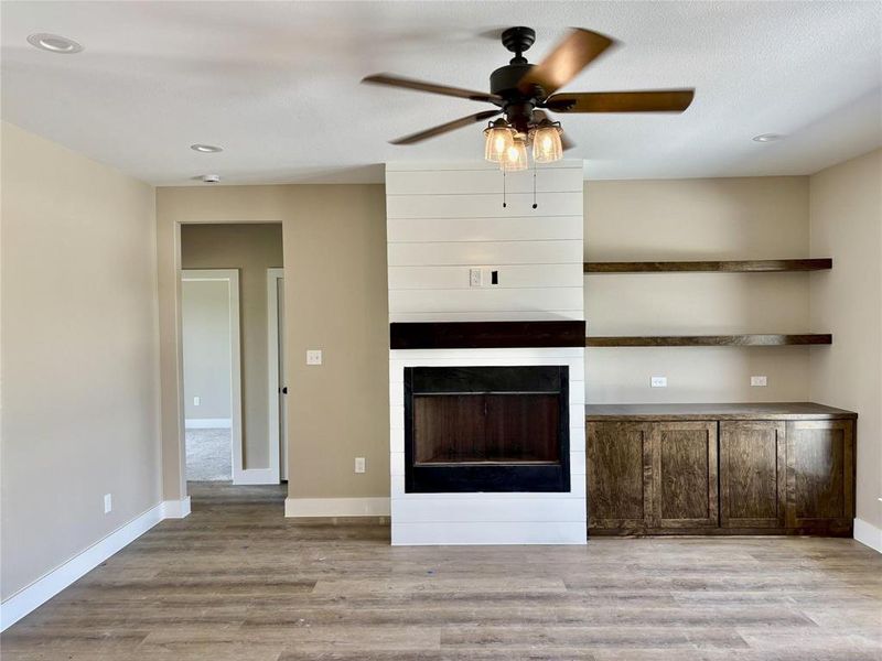 Unfurnished living room featuring a fireplace, a ceiling fan, light wood-style flooring, and recessed lighting