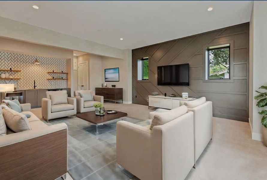 Living area featuring bar with sink, an accent wall, and recessed lighting
