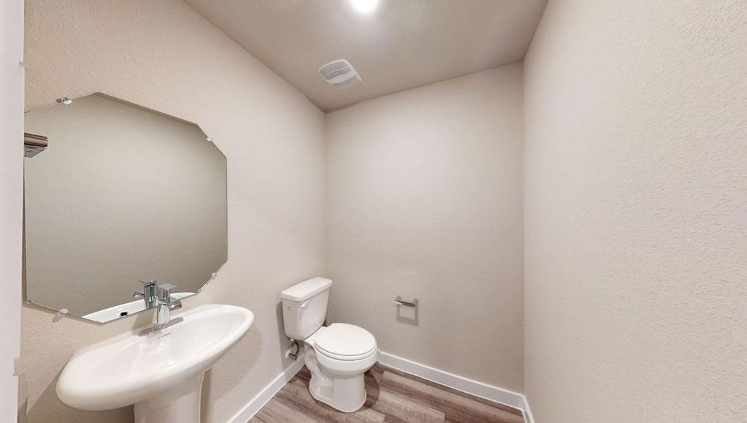 Half bathroom with light wood-type flooring and toilet