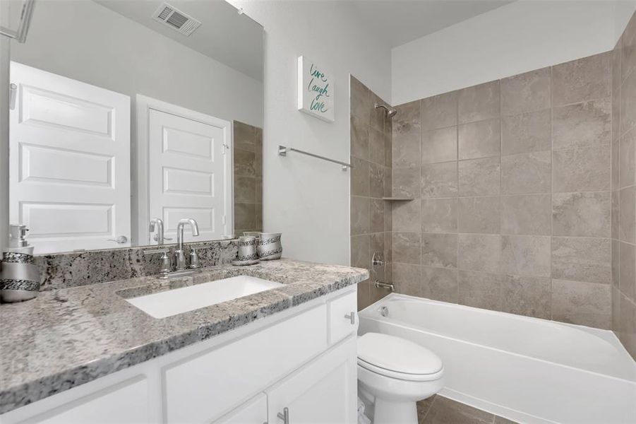 Full bathroom with toilet, vanity, tile patterned floors, and tiled shower / bath