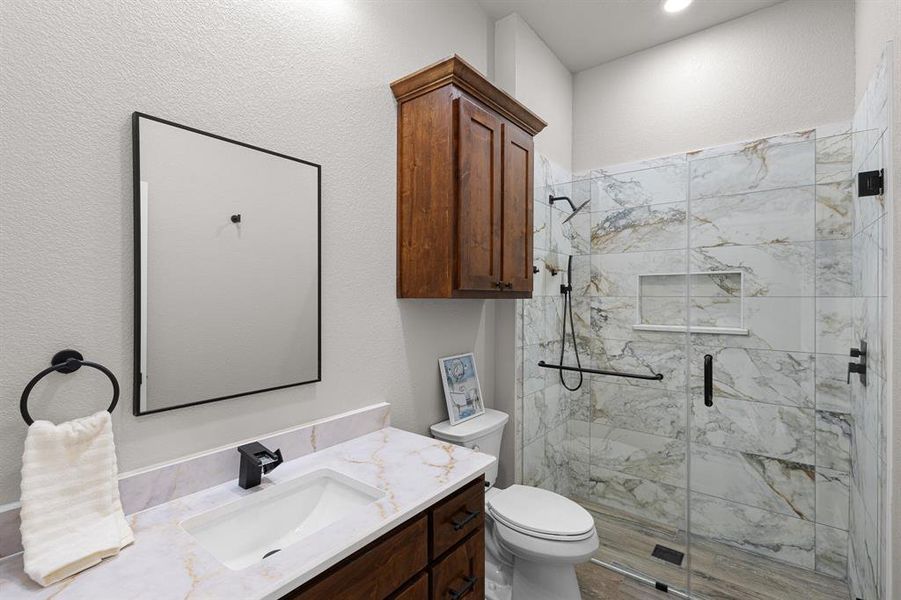 Full bathroom with vanity, a marble finish shower, and a textured wall