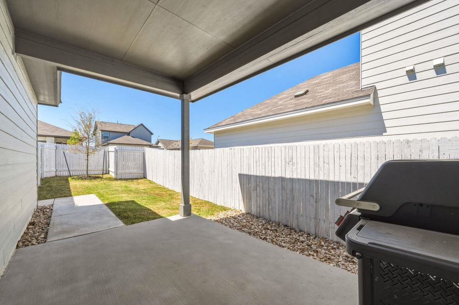 Fenced backyard featuring a patio and a grill