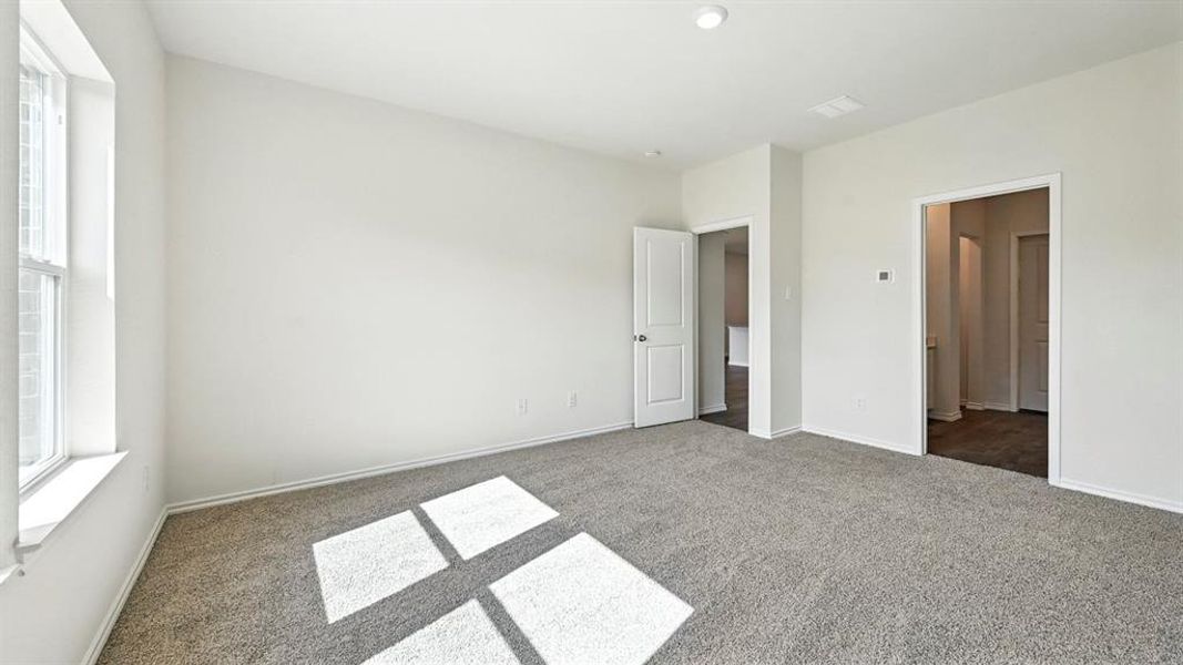 Spacious room featuring neutral carpeting, white walls, a large window, a ceiling-mounted light fixture, and two interior doorways