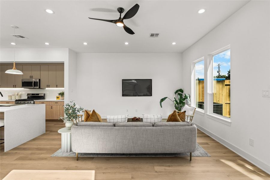 The living room offers a clean layout with a large wall perfectly sized for a media center or TV. High transom windows are placed along the wall to bring in extra light and views of the sky while keeping the space completely private from neighboring homes.