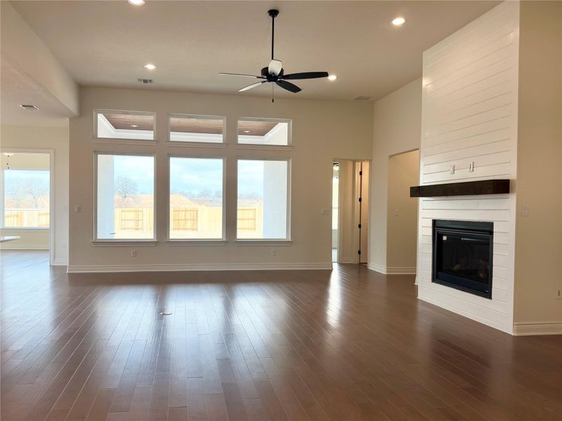 Unfurnished living room featuring ceiling fan, a large fireplace, dark wood-style flooring, and recessed lighting