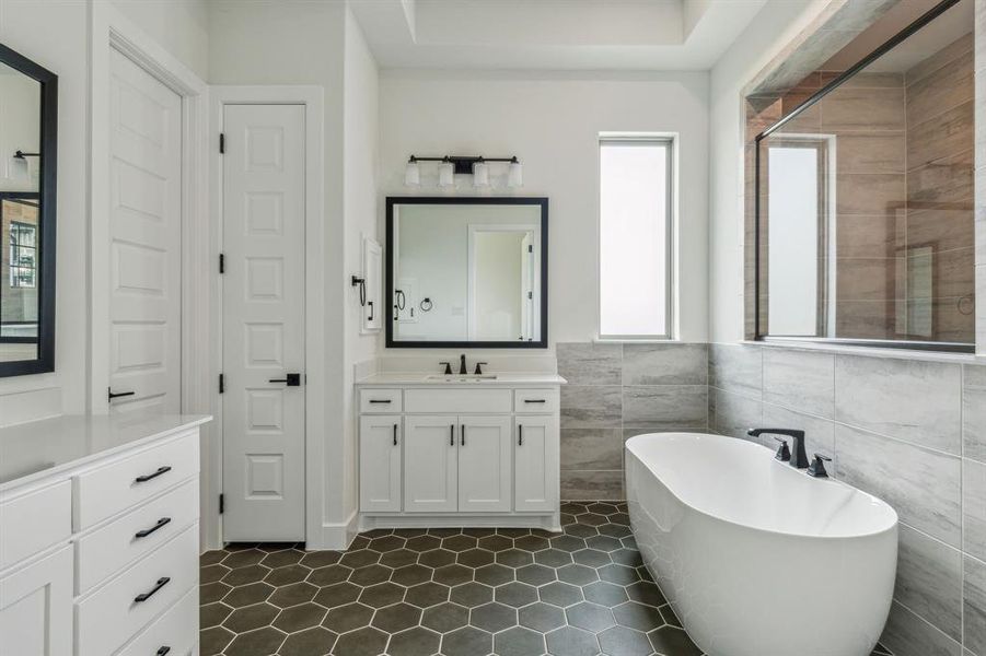 Bathroom featuring vanity, a bath, and tile walls