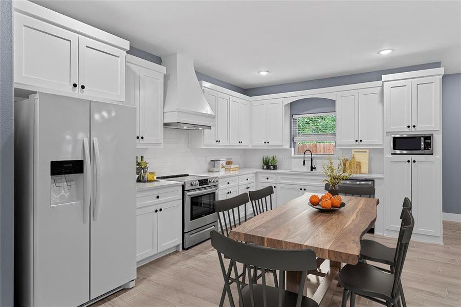 Kitchen featuring appliances with stainless steel finishes, premium range hood, white cabinets, and recessed lighting Kitchen featuring appliances with stainless steel finishes, premium range hood, white cabinets, and recessed lighting