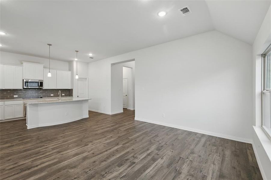 Kitchen featuring dark wood-style flooring, stainless steel microwave, white cabinetry, and a center island with sink Kitchen featuring dark wood-style flooring, stainless steel microwave, white cabinetry, and a center island with sink