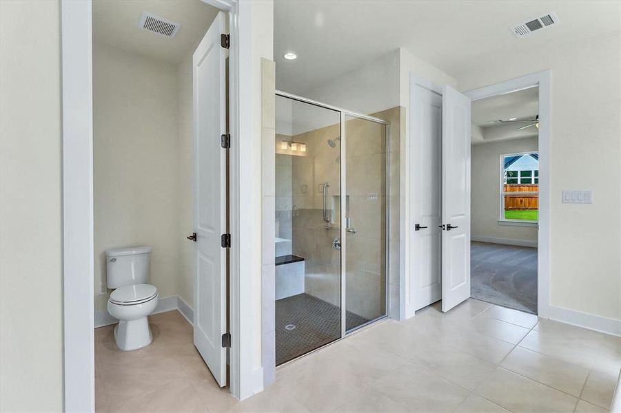 Spacious bathroom featuring a glass-enclosed shower with a built-in bench, a separate water closet, tile flooring, and clean white trim Spacious bathroom featuring a glass-enclosed shower with a built-in bench, a separate water closet, tile flooring, and clean white trim