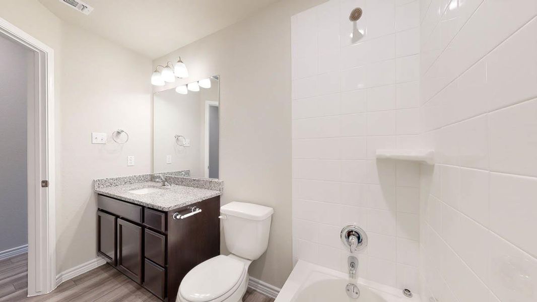 Bathroom featuring a dark wood-finish vanity with a light speckled countertop, an undermount sink, and a chrome faucet