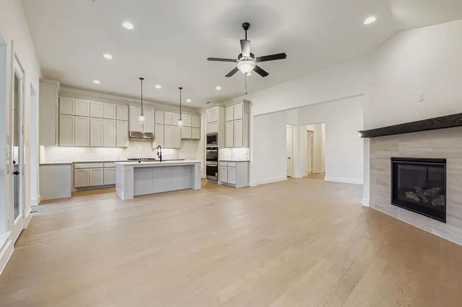 Kitchen featuring open floor plan, light wood finished floors, a center island with sink, recessed lighting, and decorative backsplash