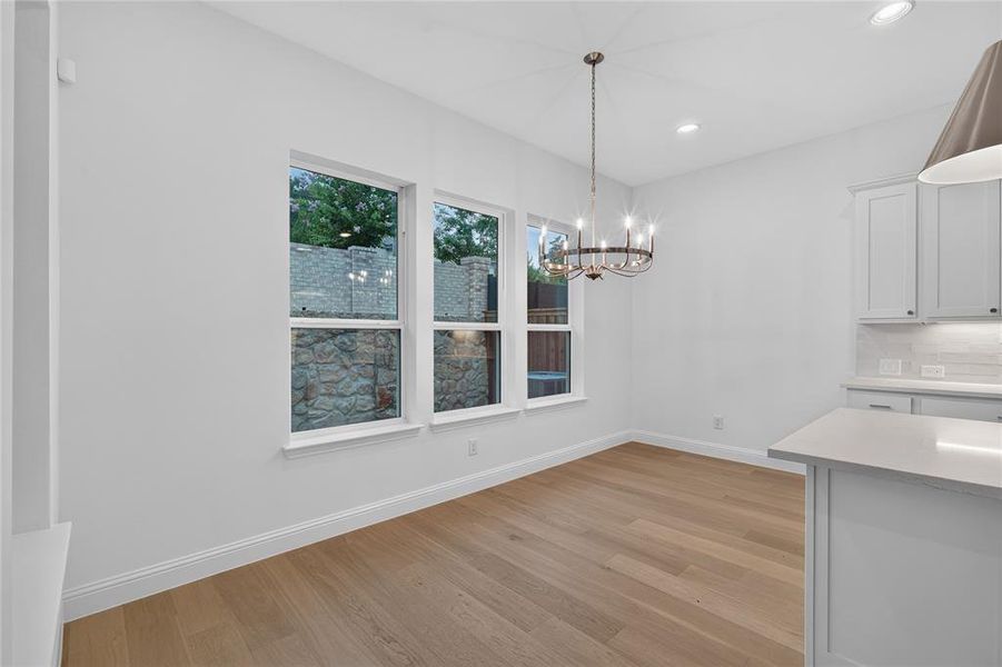 Spacious room with wood-finish flooring, three large windows, a multi-bulb chandelier, and recessed lighting Spacious room with wood-finish flooring, three large windows, a multi-bulb chandelier, and recessed lighting