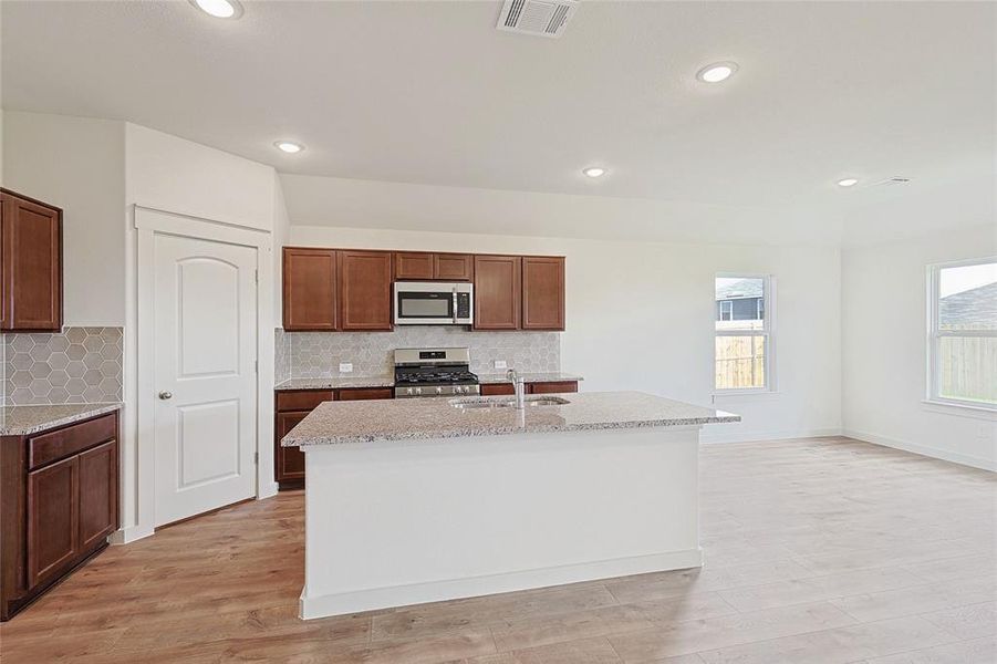 Kitchen with stainless steel appliances, a wealth of natural light, and a kitchen island with sink