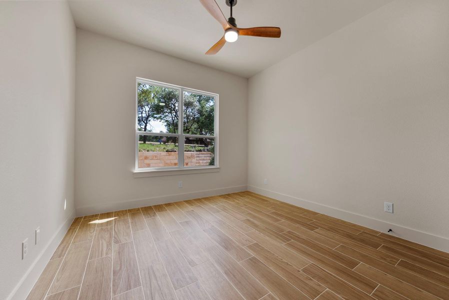 A well-lit room showcases durable wood-look tile flooring and a window offering green views.