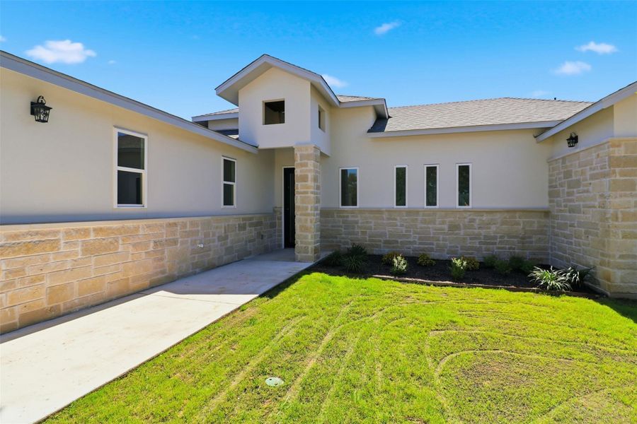 Contemporary stucco and stone exterior featuring multiple window styles, recessed entryway, concrete walkway, and a landscaped garden bed Contemporary stucco and stone exterior featuring multiple window styles, recessed entryway, concrete walkway, and a landscaped garden bed