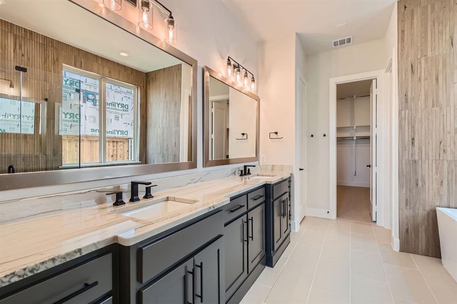 Full bathroom featuring double vanity, a freestanding tub, tile patterned floors, and a spacious closet Full bathroom featuring double vanity, a freestanding tub, tile patterned floors, and a spacious closet