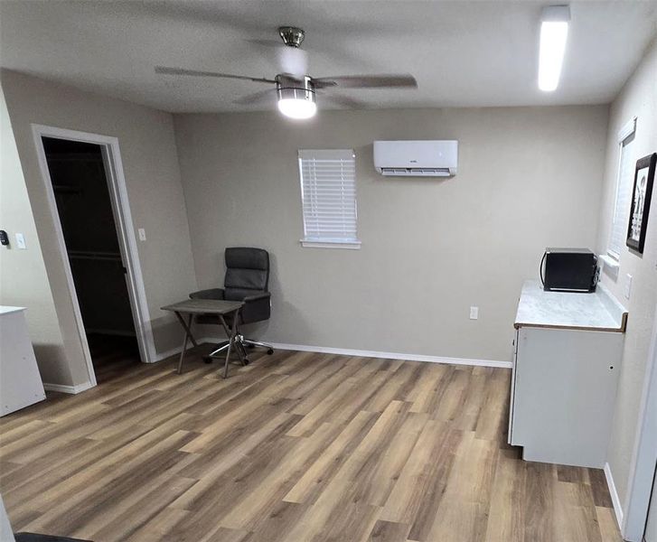 Office area featuring light wood-type flooring, ceiling fan, and a wall mounted air conditioner.