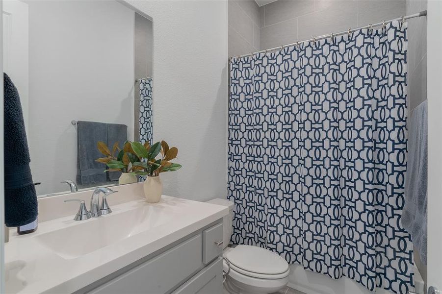 Bathroom with curtained shower, vanity, and toilet