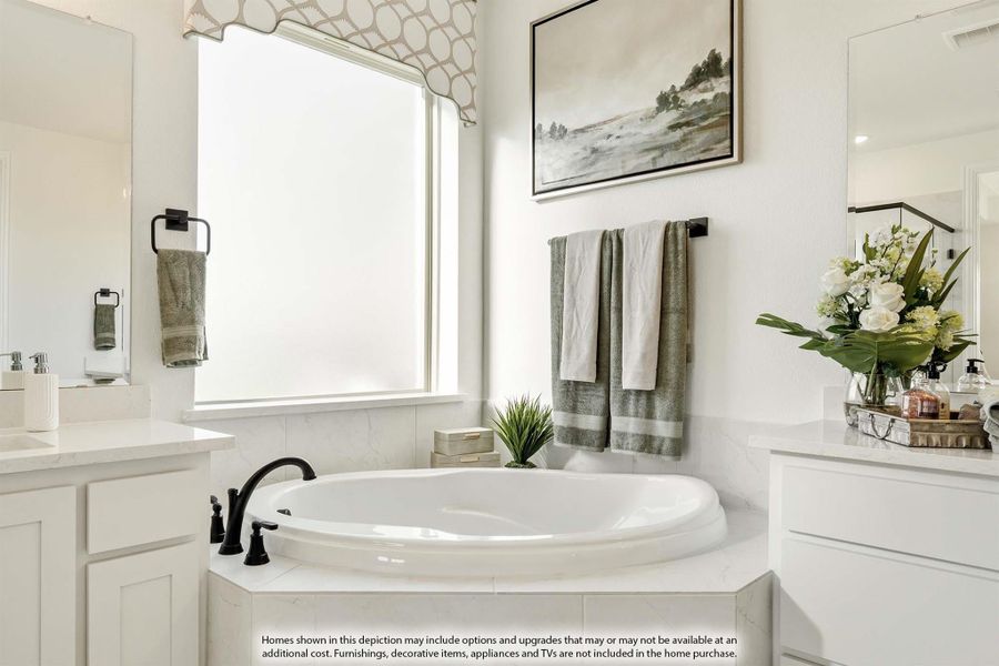 Master bathroom with oval soaking tub, white cabinets, marble surround, and large window