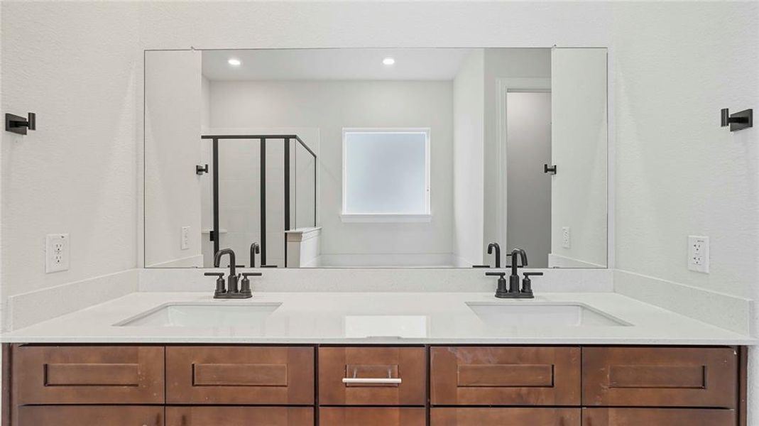 Dual vanity featuring a long integrated mirror, two undermount sinks, and dark wood-finish cabinetry