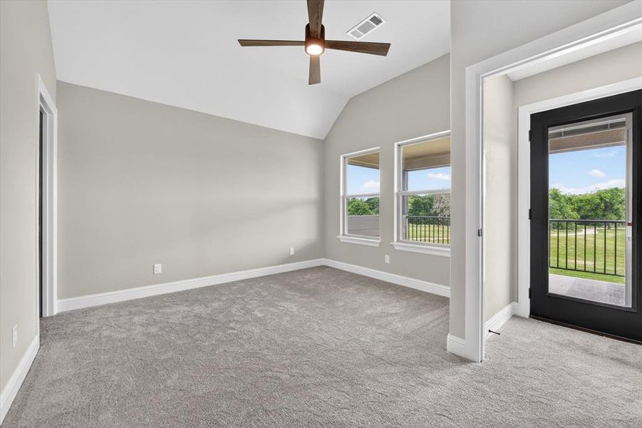 Carpeted room featuring a vaulted ceiling with a ceiling fan, three pane windows, a glass-paned door, and white trim