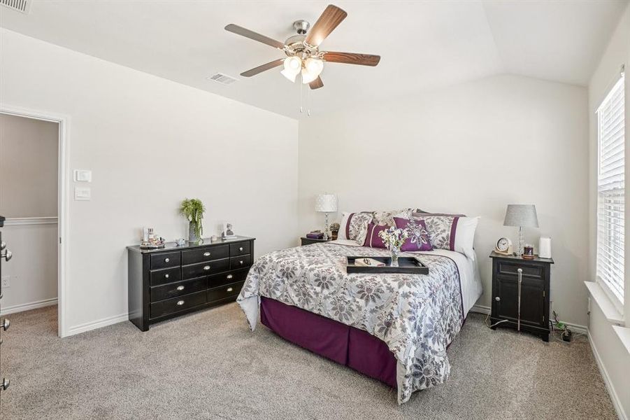 Bedroom with carpet flooring, vaulted ceiling, and a ceiling fan Bedroom with carpet flooring, vaulted ceiling, and a ceiling fan