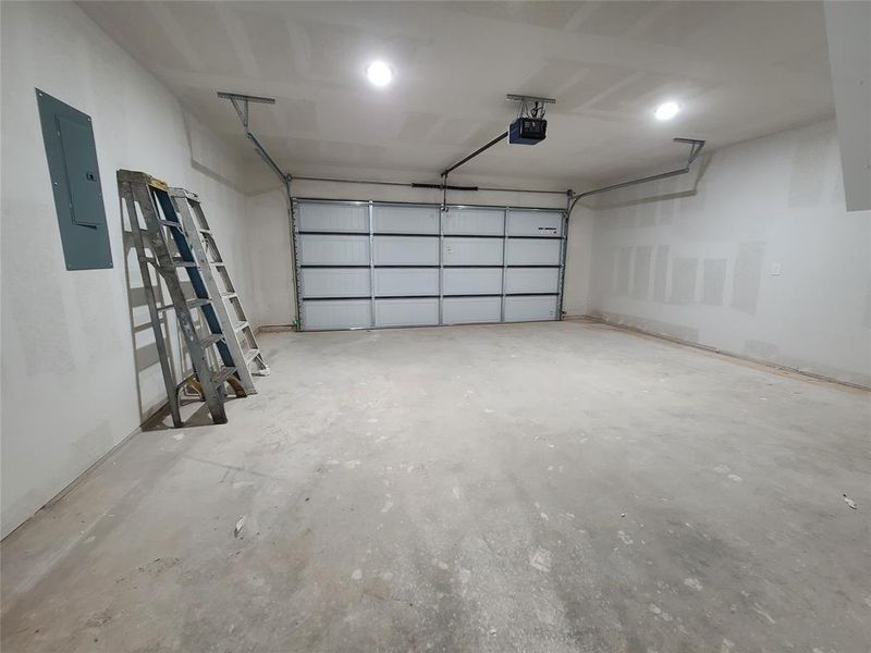 Garage featuring electric panel and a garage door opener