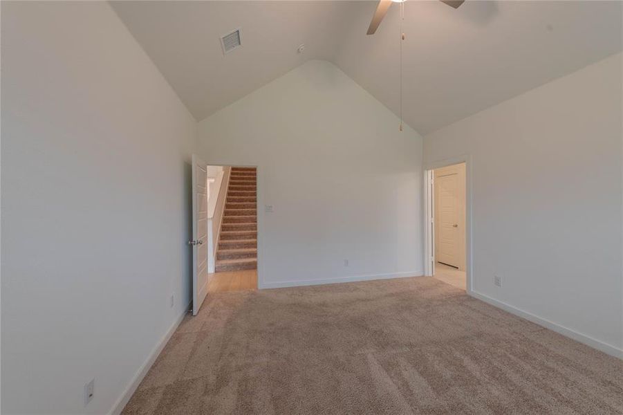 Spare room with a ceiling fan, light colored carpet, high vaulted ceiling, and baseboards